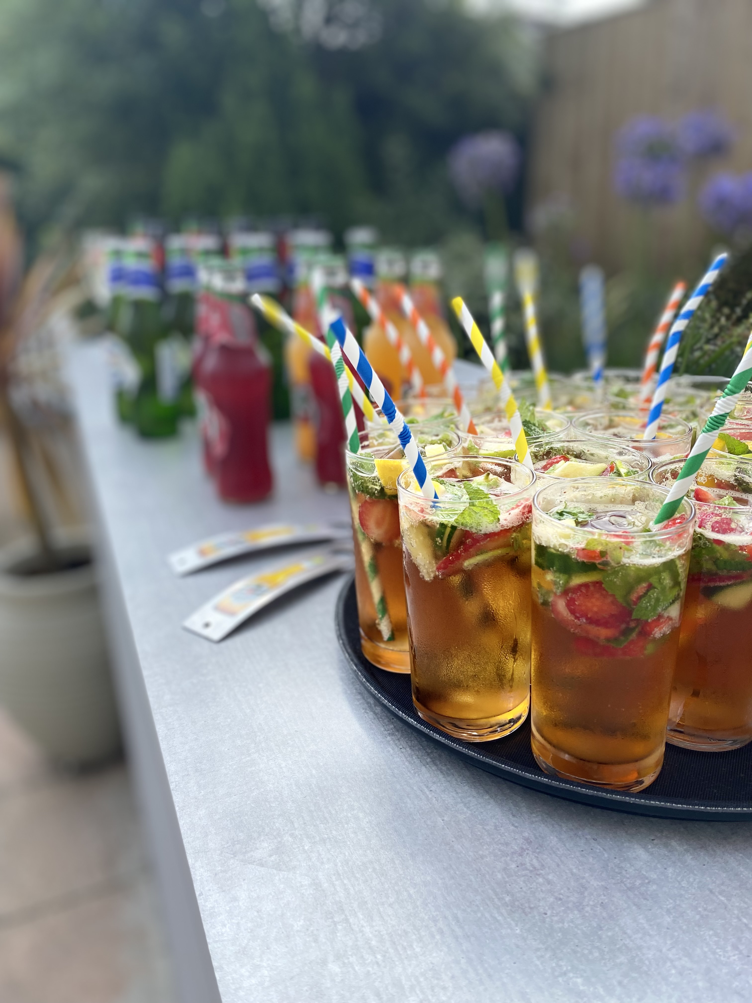 Tray of Pimm's cocktails in the outdoor garden with striped straws